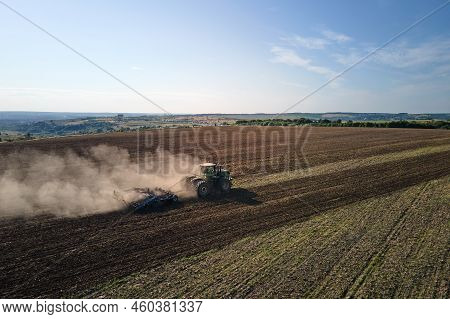 Aerial View Of Tractor Plowing Agriculural Farm Field Preparing Soil For Seeding In Summer.