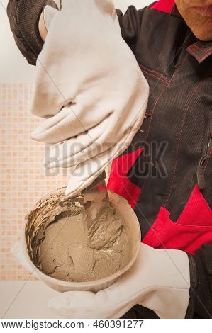 Older Man Working In Empty Apartment Repairing Holes In Walls