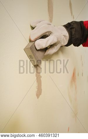 Older Man Working In Empty Apartment Sanding Repair Walls Before Painting