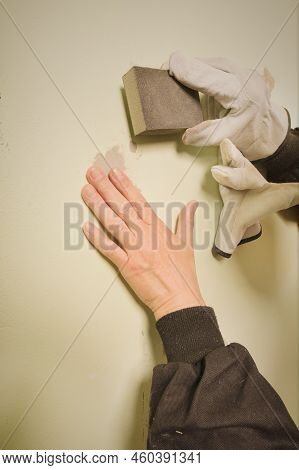 Older Man Working In Empty Apartment Sanding Repair Walls Before Painting