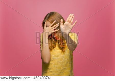 Scared Or Embarrassed Young Girl Covering Eyes With Hands And Doing Stop Gesture On Pink Studio Back