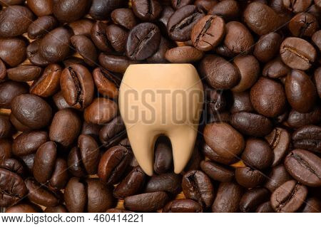 Large Coffee Stained Tooth On A Pile Of Roasted Coffee Beans. Creative Teeth Whitening Concept.
