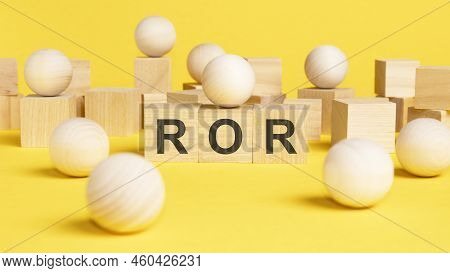 The Text Ror Is Written On Wooden Cubes On A Bright Yellow Surface. Wooden Sphere Balls Among The Wo