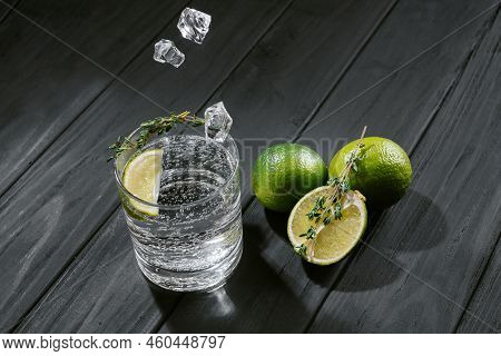 Hard Seltzer With Lime On A Dark Wooden Background, Ice Cubes Fall Into A Glass With An Alcoholic Dr