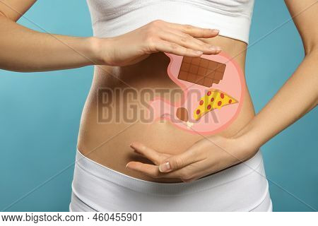 Woman With Image Of Stomach Full Of Junk Food Drawn On Her Belly Against Light Blue Background, Clos