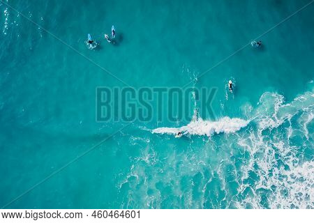 Surfers In Blue Transparent Ocean And Waves. Aerial View