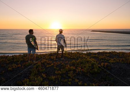 Surfers Watching The Waves At Sunset