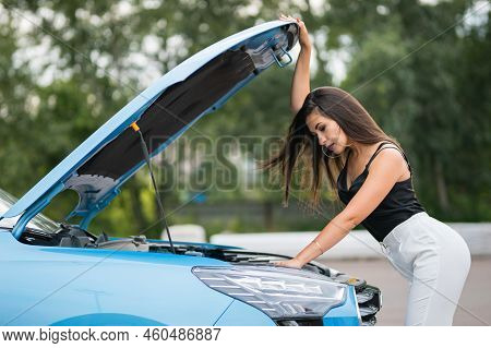 Elegant Black-haired Businesswoman Tries To Repair Blue Car On Parking Lot. Woman Driver Has Motivat