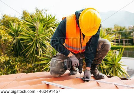 Technical Worker Works With Drill On The Roof Of A House