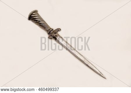 The Dagger Is An Old Landsknecht Or A Steel Dagger For The Left Hand Isolated On A White Background,