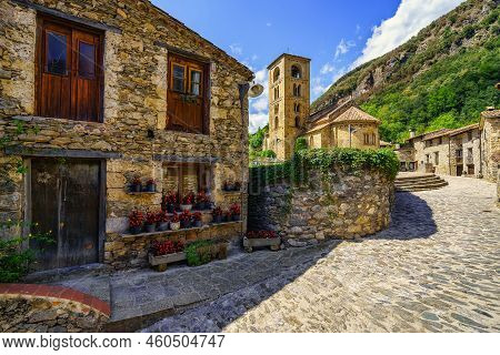 Picturesque Alley With Houses Full Of Flowers And Main Square With Romanesque Church In The Mountain