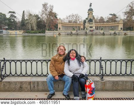 Romantic Scene Of A Smiling Middle-aged Couple Sitting On A Step Against The Water Of Grand Pond Or 