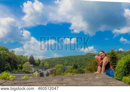 Viewpoint With Partial Cityscape Of Clervaux Surrounded By Lush Green Trees In Background, Smiling M