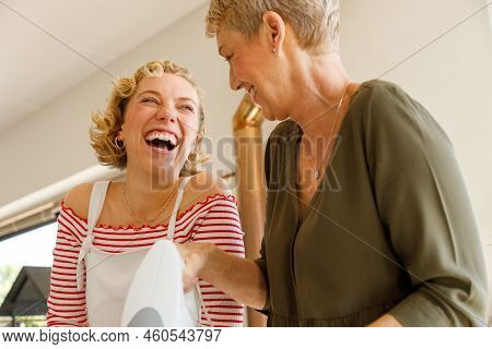 Low Angle View Of Caucasian Mother And Daughter Laughing And Looking At Each Other While Mixing Batt