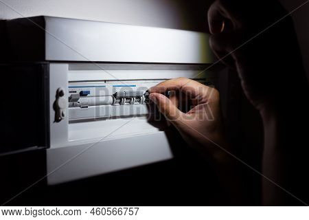 Blackout Concept, Energy Crisis. Hand Holding A Flashlight To Investigate A Home Fuse Box