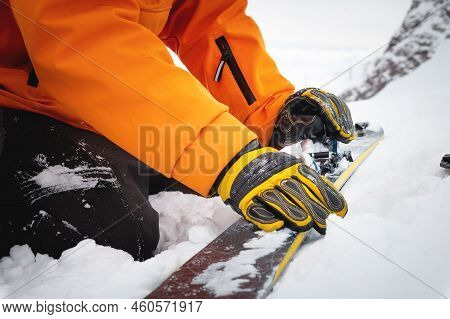 Close-up Of A Mans Hand, Adjusting The Skis Against The Background Of Snow And Things, Putting On Th