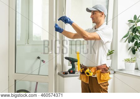 A Repairman Repairs, Adjusts Or Installs Metal-plastic Windows In The Apartment. Glazing Of Balconie