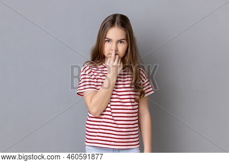Dont Lie. Little Girl Wearing Striped T-shirt Looking With Incredulous Gaze And Touching Nose, Gestu