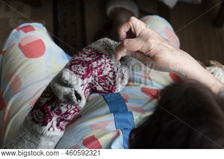 Close Up Of Old Lady Hands Darning Winter Socks With Hole. Poverty In World Economic Crisis Concept