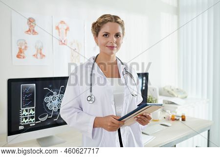Portrait Of Female General Practitoner With Tablet Computer Standing In Medical Office And Looking A