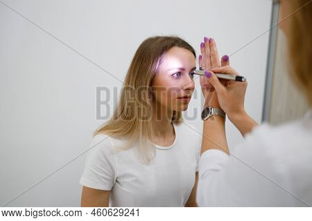 Doctor Neurologist Shining Flashlight On Patient Eyes To See Pupil Reaction To Light In Clinic
