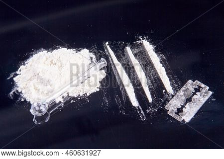 Pile Of White Powder Drugs And Glass Smoking Pipe. Razor And Cocaine Lines For Snorting.
