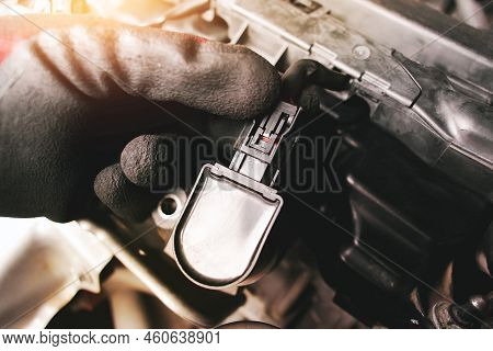 The Auto Mechanic Is Unplugging The Ignition Coil Of The Car Engine In The Engine Compartment.