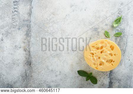 Cheese Maasdam Or Radamer. Piece Of Cheese On Black Marble Or Stone Standa On Old Grey Concrete Back