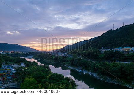 Sunrise Colors In Clouds Over Narrow River Through Small Town
