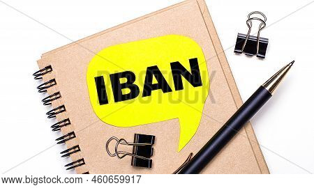 On A Light Background, A Brown Notebook, A Black Pen And Paper Clips, And A Yellow Card With The Tex