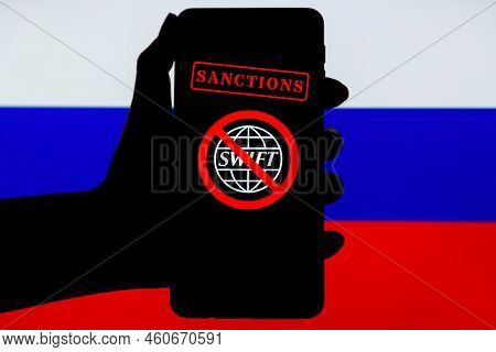 Ukraine, Kiev - February, 23 2022: Silhouette Of Black Hand Holding Mobile With Crossed Out Swift Lo