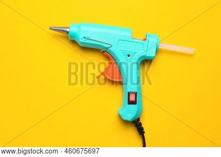 Turquoise Glue Gun With Stick On Yellow Background, Top View