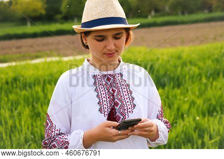 Defocus Young Ukrainian Woman Portrait. Meadow Nature Background. Sad Ukrainian Girl Scrolling Phone