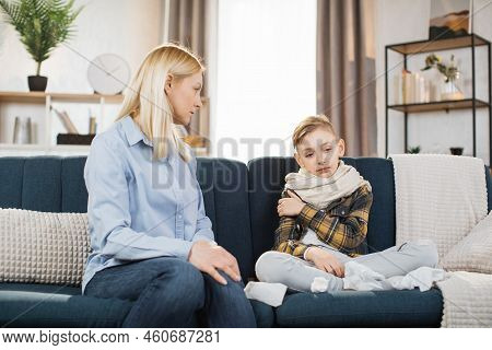 Pleasant 40-aged Caucasian Mother Measuring Temperature Of Her Teen Boy, Which Is Sitting Near Her O