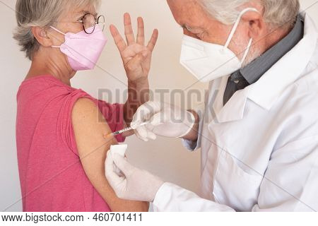 Doctor Giving Injection To Senior Caucasian Woman, Female Receiving Fourth Booster Of Covid 19 Vacci
