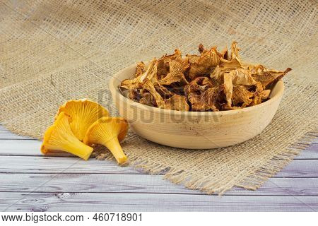 Dry Golden Chanterelles In Wooden Bowl And Fresh Girolle Mushrooms On Table On Jute Burlap