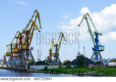 Harbor Pier With Many Cranes And Stacks Of Bulk Cargo, Coal And Wood Chips