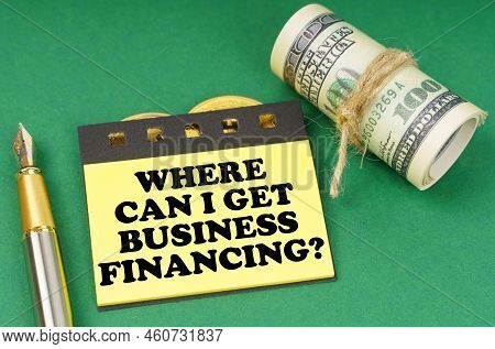 Business Concept. On A Green Surface Are A Pen, Dollars And Yellow Stickers With The Inscription - W