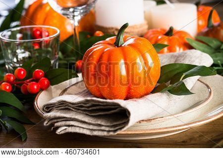 Table Setting With Plate, Pumpkin And Candles At Wooden Table. Autumn Table Decorations. Thanksgivin