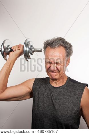 Mature Man 60plus Working Out With Weights At Home Doing Shoulder Press With One Arm