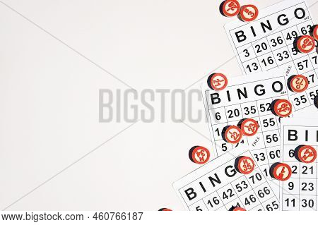 Many Wooden Chips With Numbers And Cards For A Board Game Of Bingo Or Lotto On A Light Background.