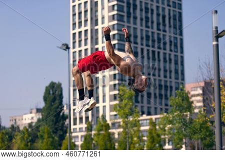 Backflip. Lifestyle Portrait Of Athlete, Muscular Shirtless Man Workout At Sports Ground At Public P