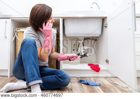 Woman Sitting Near Leaking Sink Sking For Help By Phone