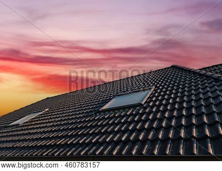 Open Roof Window In Velux Style With Black Roof Tiles During Sunset.