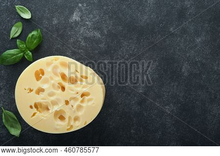 Cheese Maasdam Or Radamer. Piece Of Cheese On Black Marble Or Stone Standa On Black Concrete Backgro