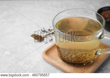Cup Of Aromatic Buckwheat Tea And Granules On Light Marble Table. Space For Text