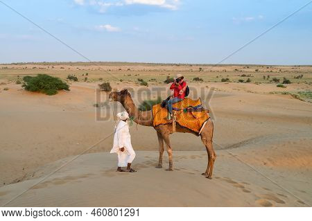 Female Tourist Taking Picture While Riding Camel, Camelus Dromedarius, At Sand Dunes Of Thar Desert,