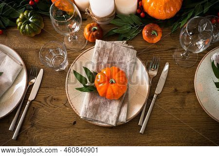 Autumn Table Setting With Craft Plate, Cutlery, Pumpkin And Candles At Oak Table. Thanksgiving Food 