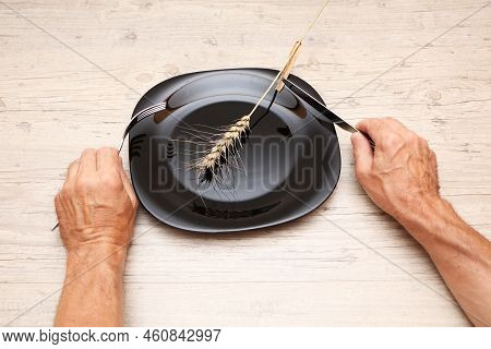 On A Black Plate, An Ear, In The Hands Of A Fork And A Knife. A Symbol Of Hunger And Inept Housekeep