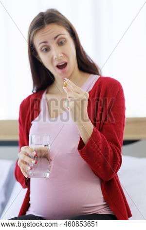 A Pregnant Woman With A Glass Of Water And A Large Pill Looked Excited. The New Mom Who Doesn't Like